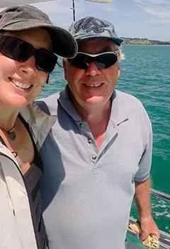 Smiling mature adult couple posing for a sunny outdoor selfie on a boat trip, representing renewed vitality and active energy.